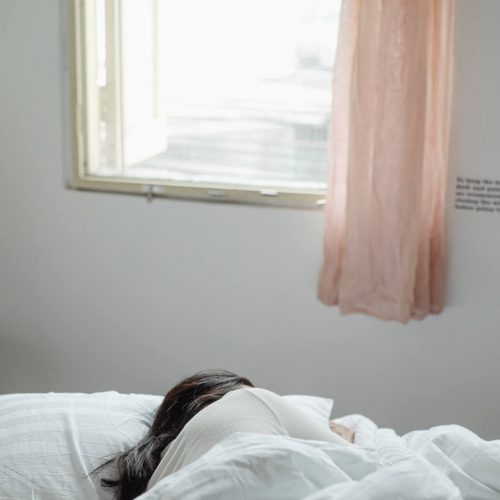 Frau schläft in Bett, unter Fenster